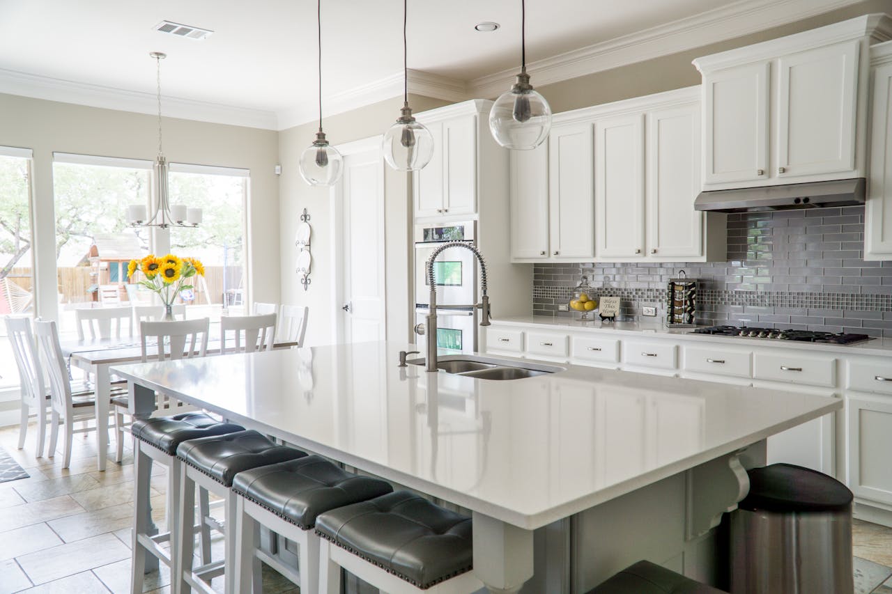 services-02 Spacious modern kitchen with white cabinets and island in natural light.